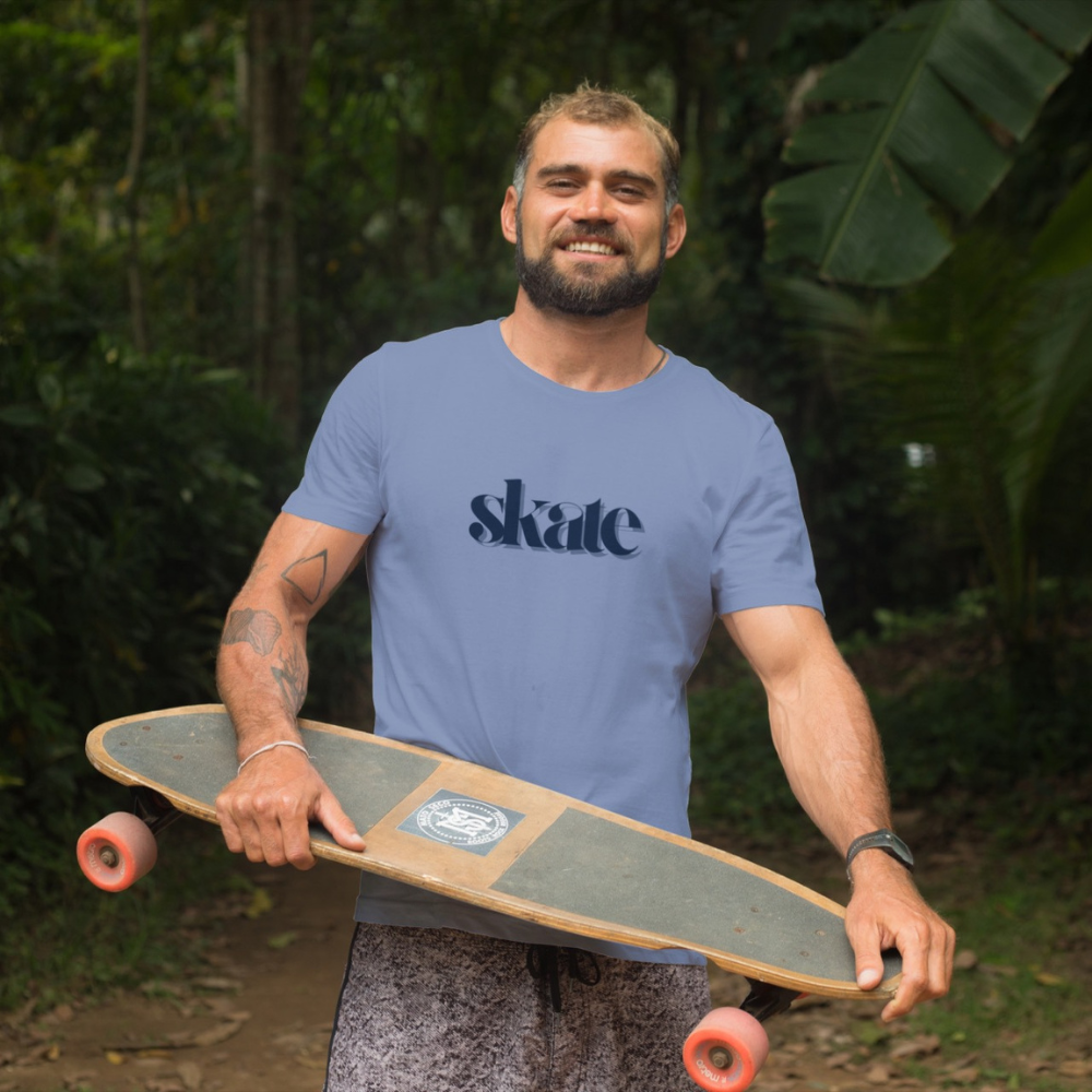 Man holding a skateboard with 'skate' t-shirt in a forest setting