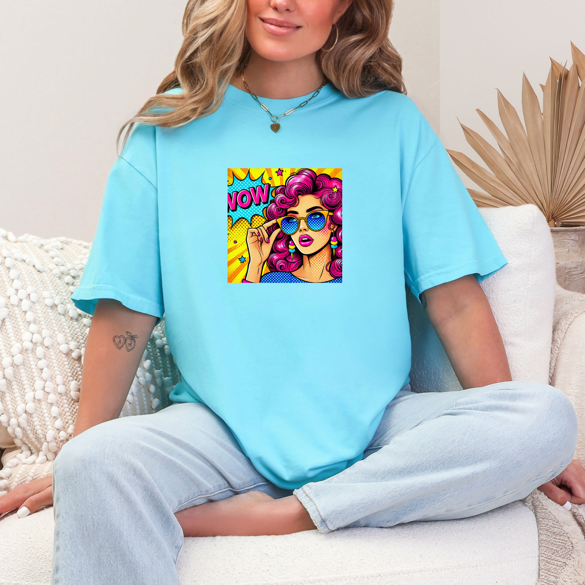 Person wearing a light blue t-shirt with a colorful graphic design sitting on a white couch.