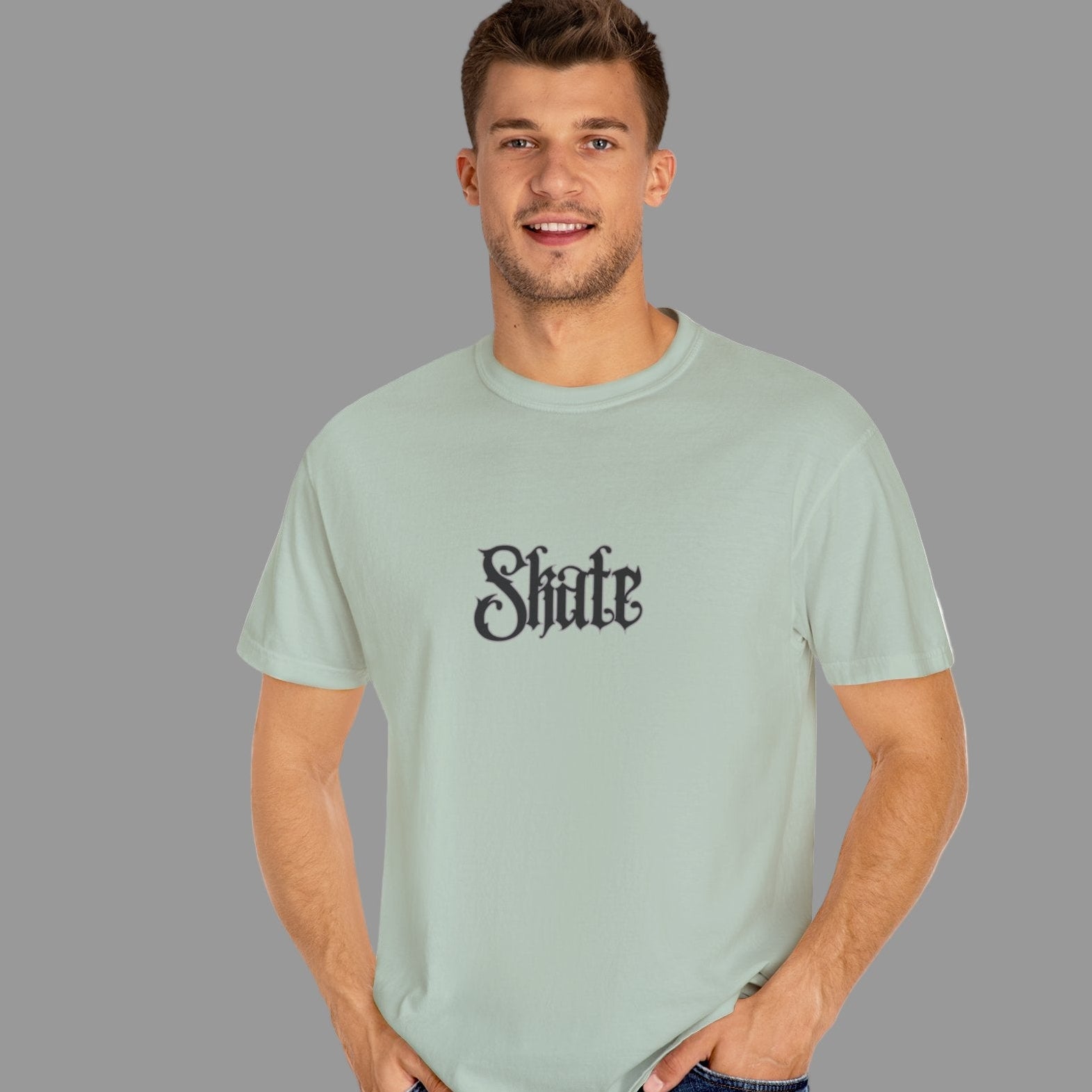 Man wearing a light green t-shirt with 'Shite' printed on it against a gray background