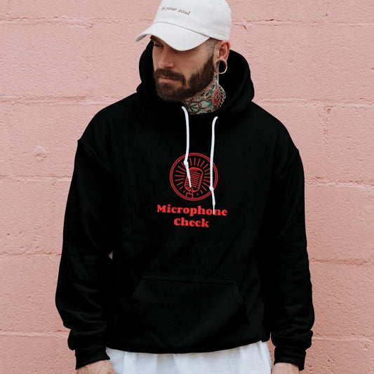 Person wearing a black hoodie with red text against a pink brick wall