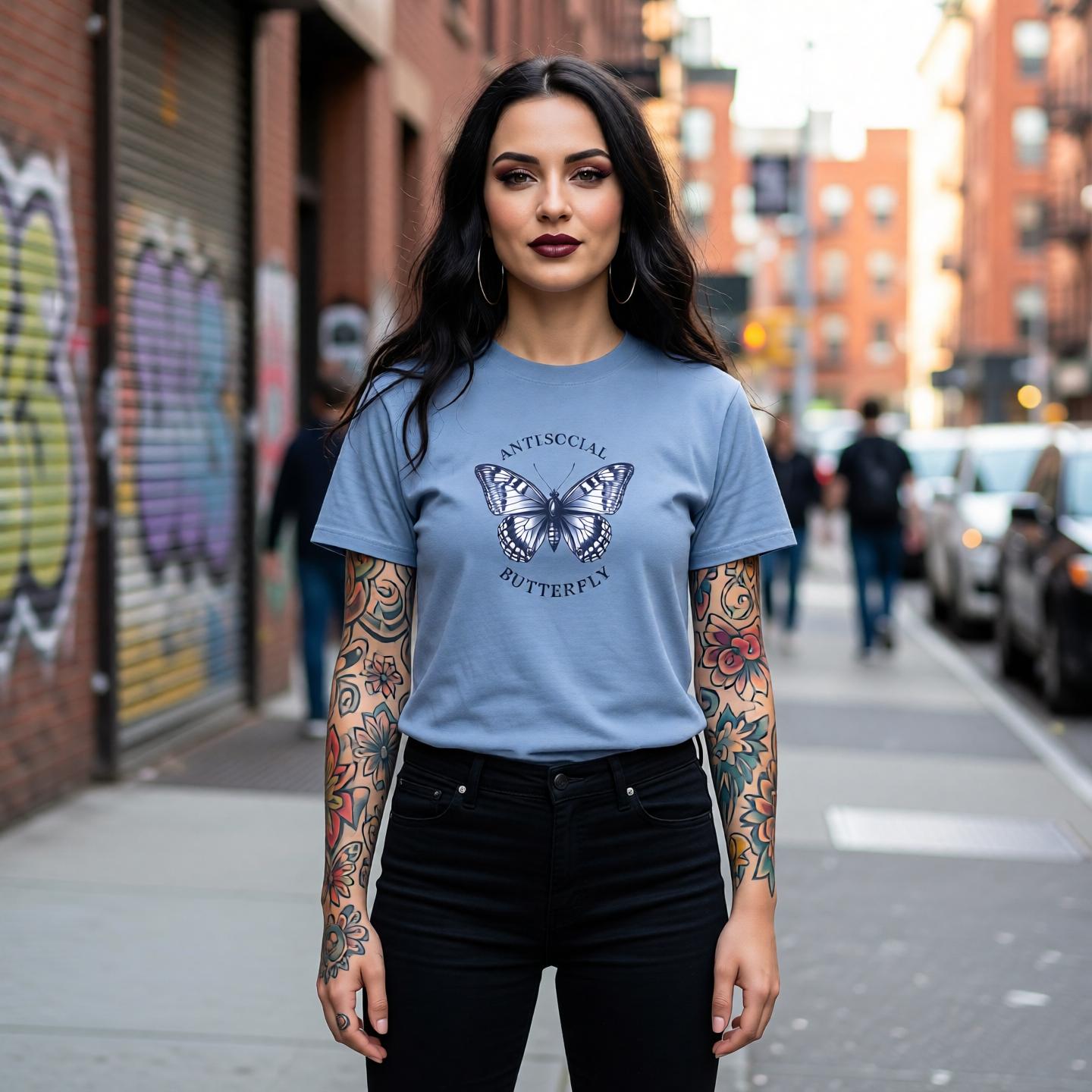 Woman wearing a blue t-shirt with a butterfly graphic on a city street.