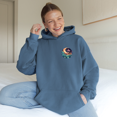 Person wearing a blue hoodie with a colorful design, sitting on a bed.