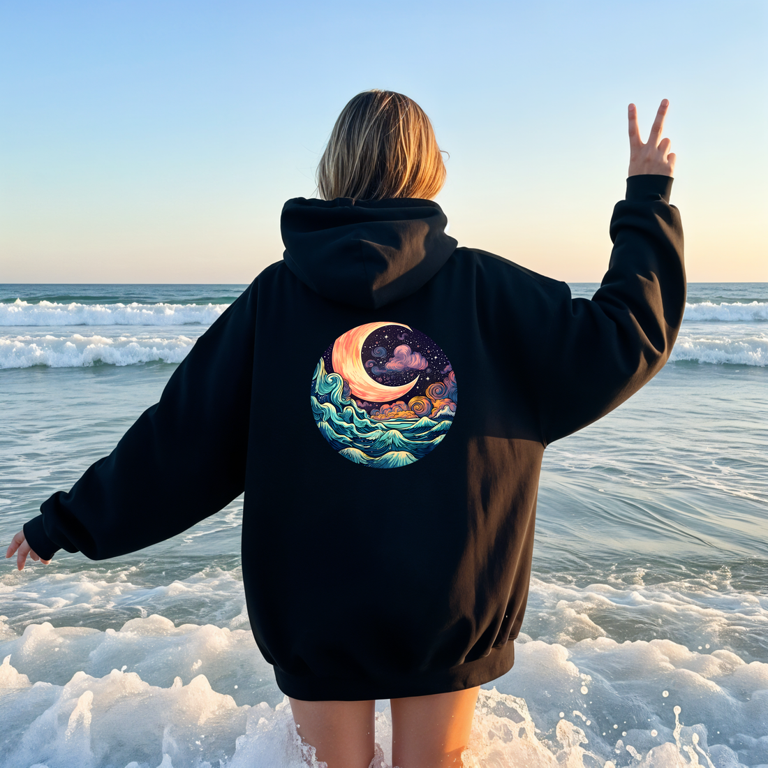 Person wearing a gray hoodie with a celestial design on the beach