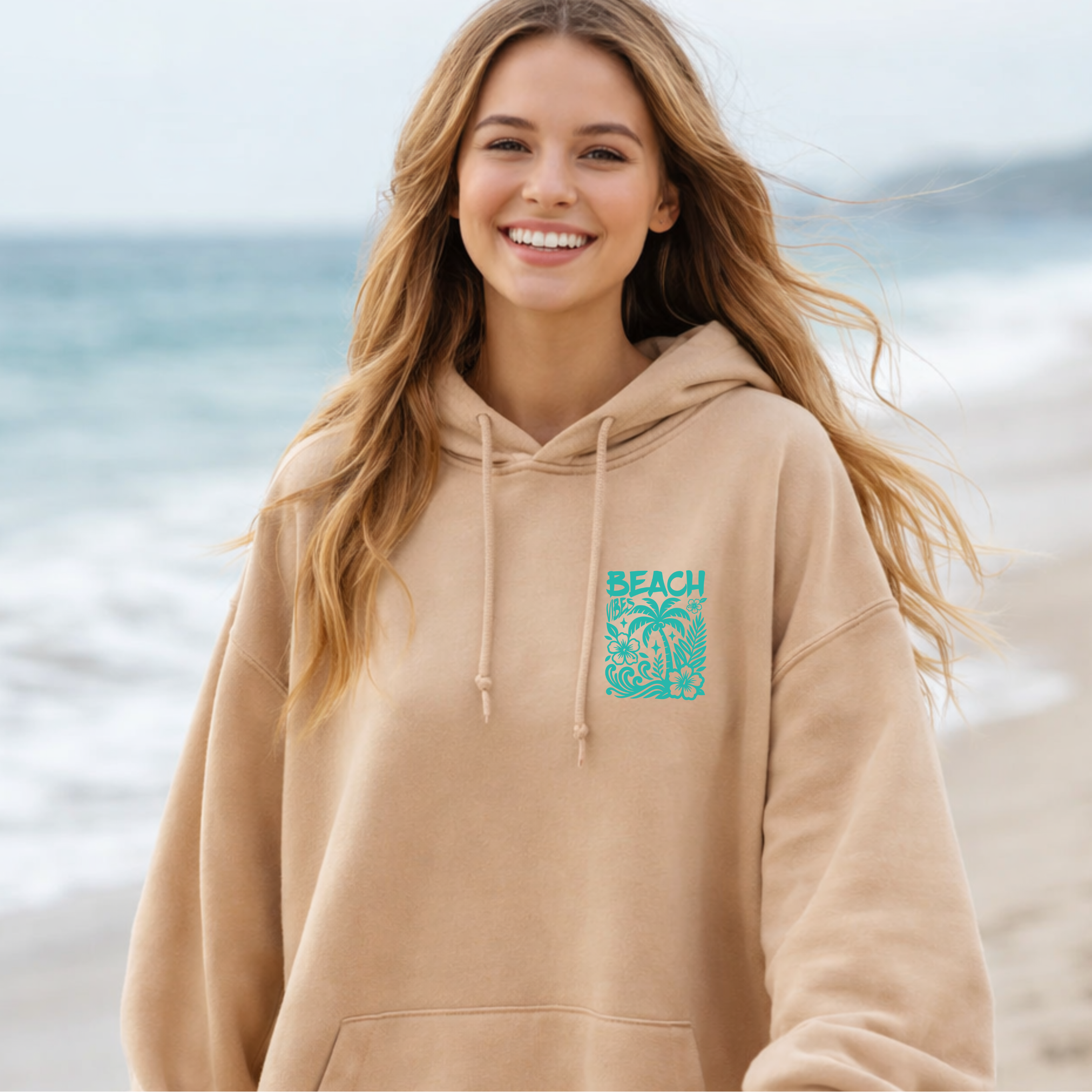Woman wearing a beige hoodie with a beach graphic palm trees and hibiscus flowers