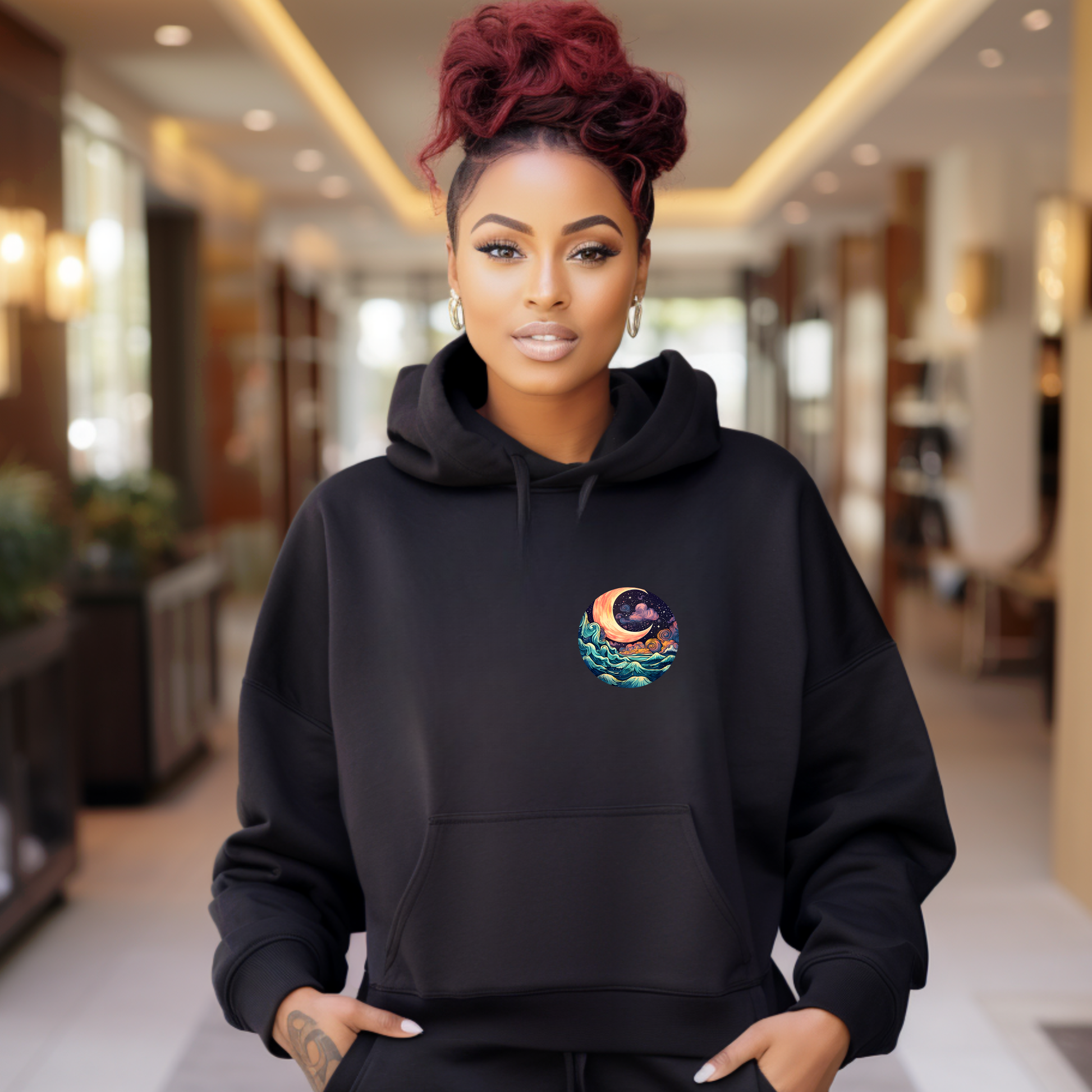 Woman wearing a black hoodie with a colorful design in a blurred indoor setting