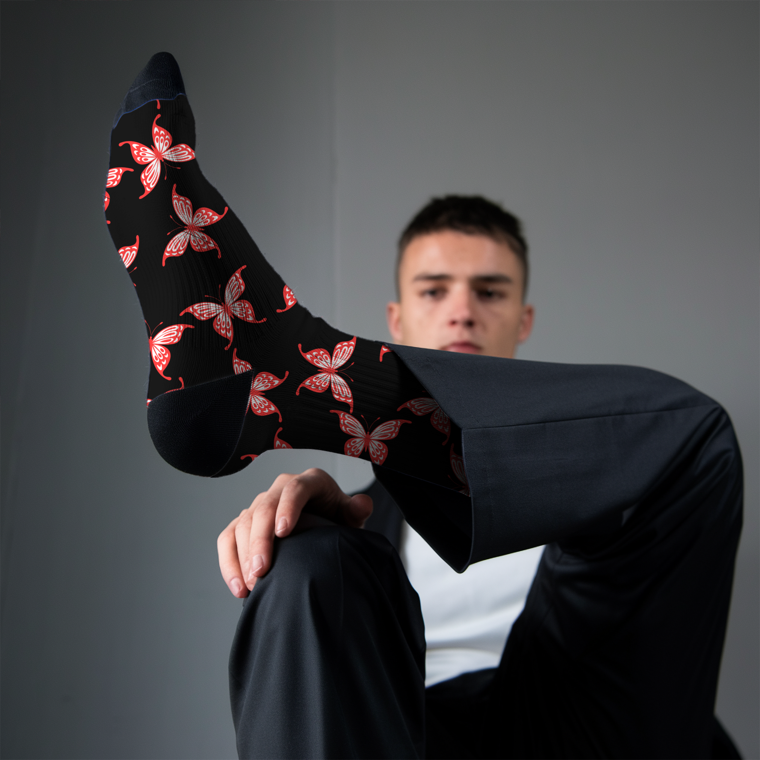 Person wearing black socks with red butterfly pattern against a gray background