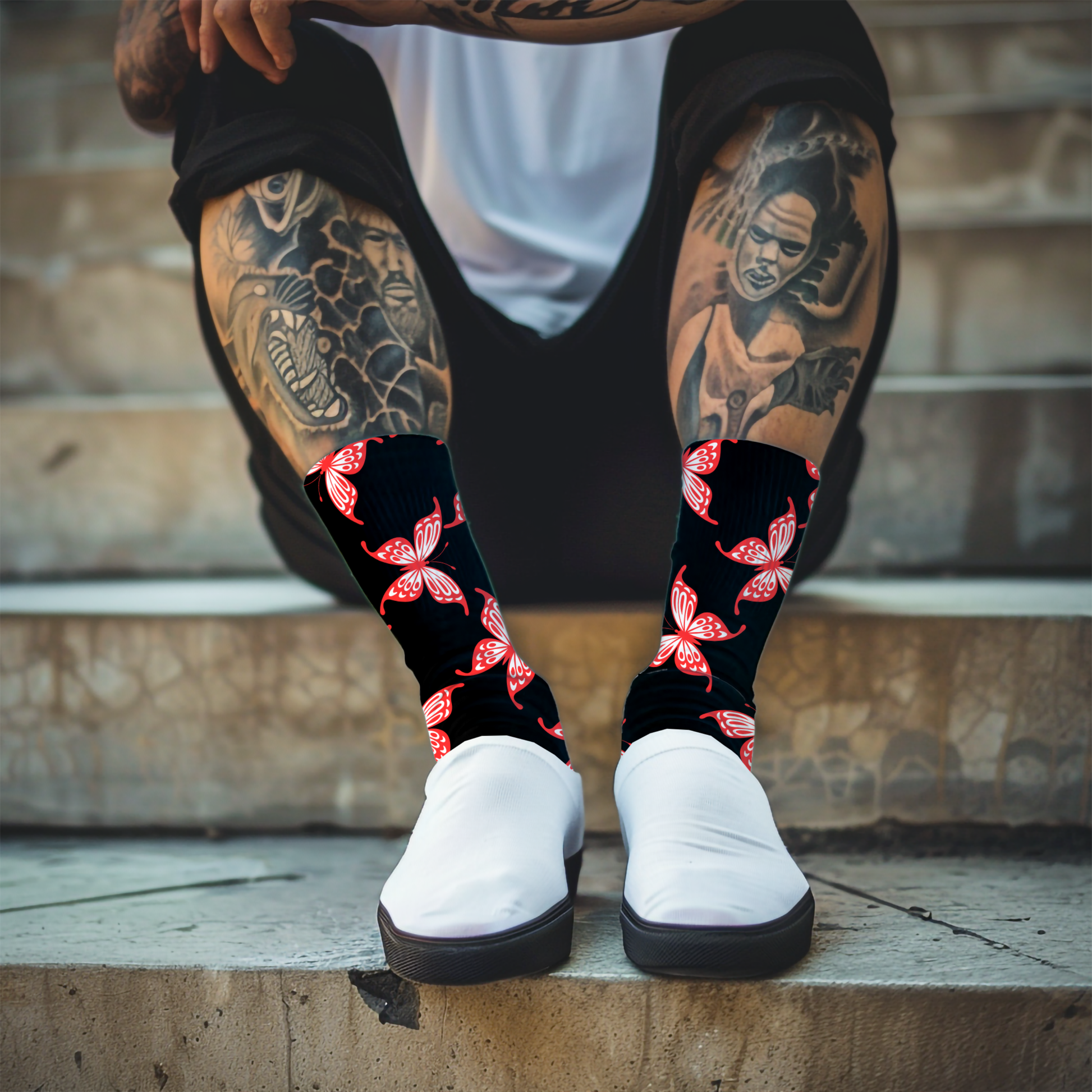 Person wearing black socks with red butterfly patterns and white sneakers on a stone step.