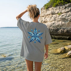 Person wearing a gray t-shirt with a blue starfish design at the beach