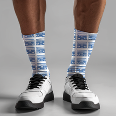 White sneakers with black laces worn on feet wearing socks with blue boom box pattern against a white background