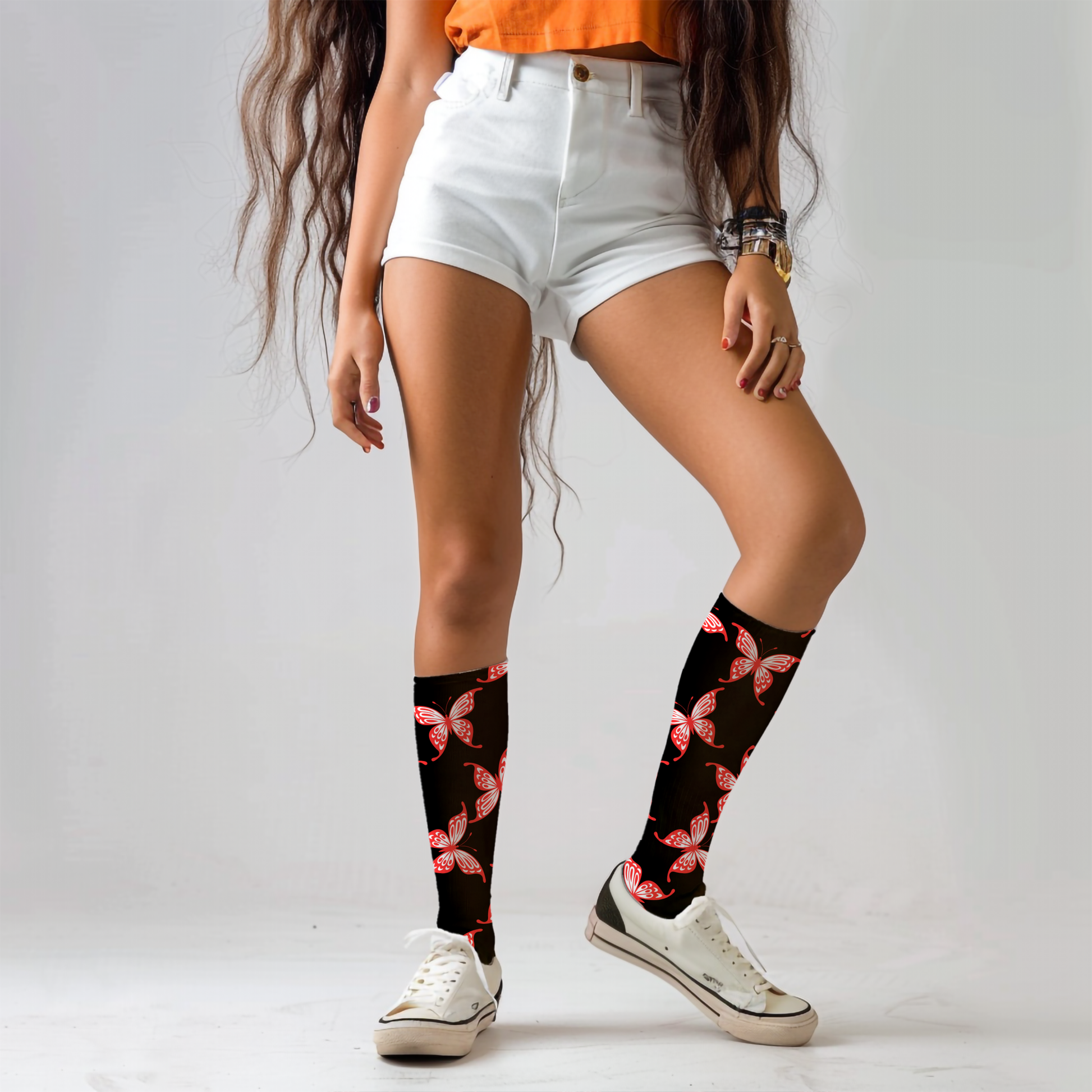 Person wearing black knee-high socks with red butterfly design on a plain background