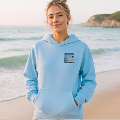 Woman wearing a light blue hoodie with a graphic design on a beach