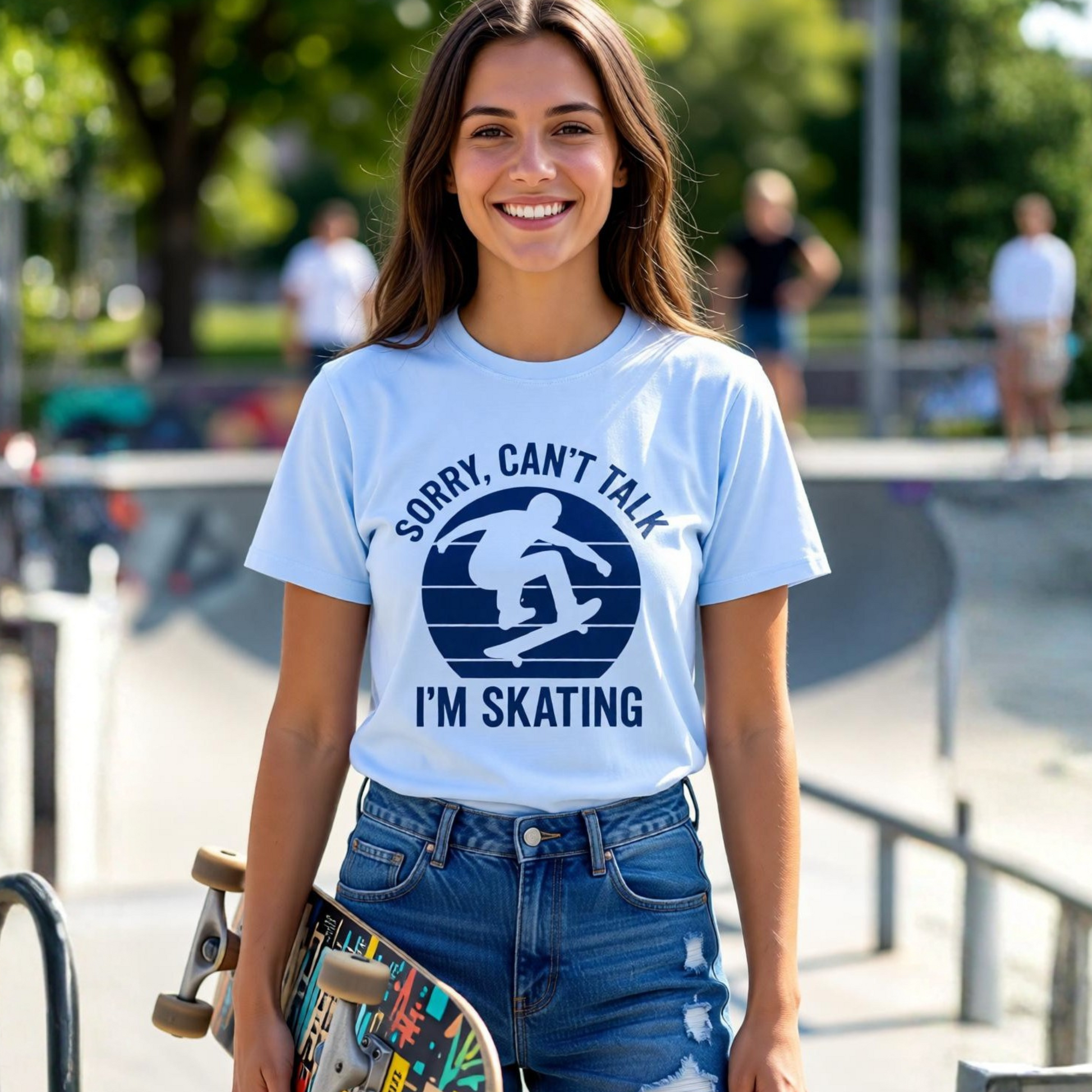Woman wearing a t-shirt with a skateboarding design and text, holding a skateboard at a skate park.