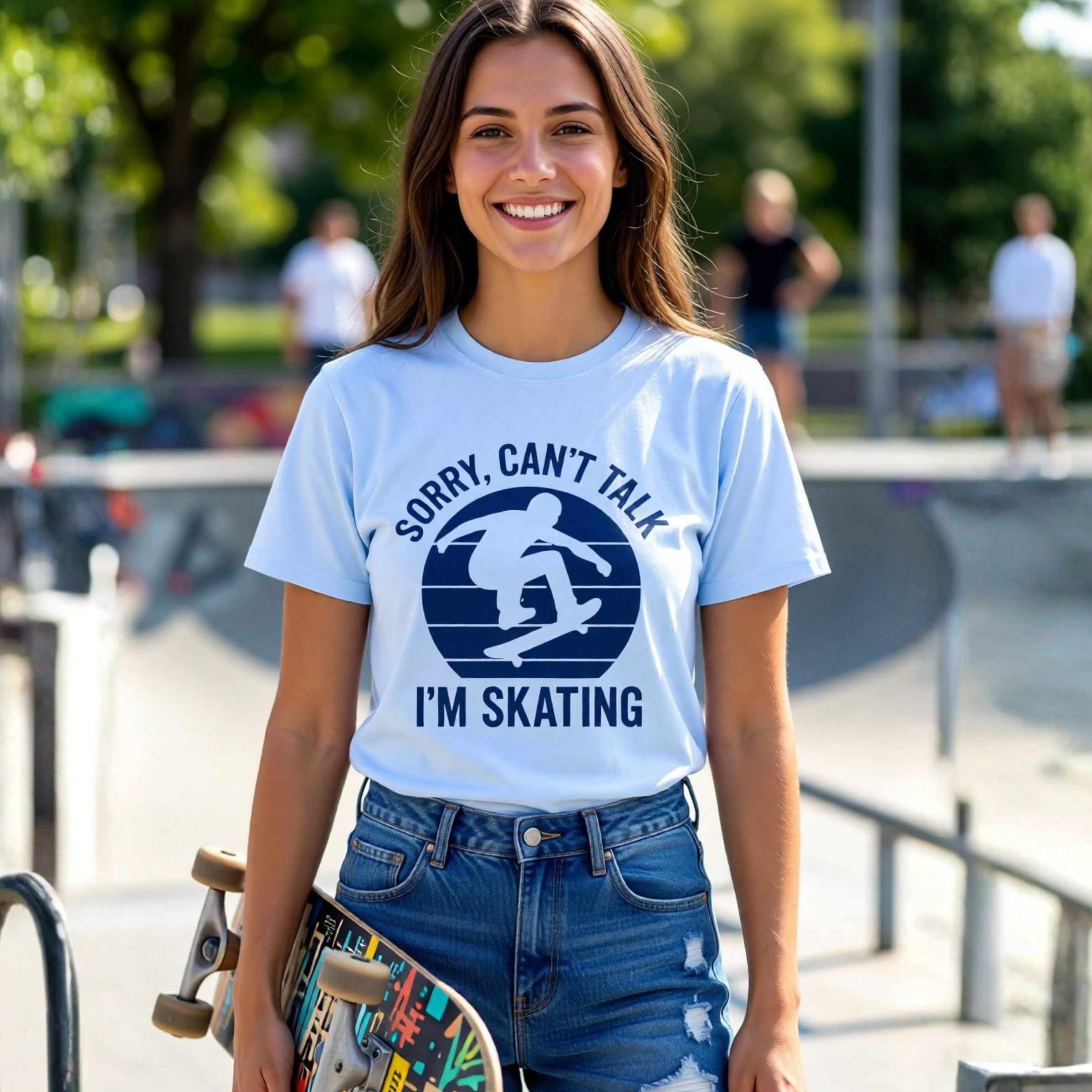 Woman wearing a t-shirt with a skateboarding design and text, holding a skateboard at a skate park.