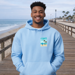 Man wearing a light blue hoodie with a beach graphic on a wooden boardwalk by the ocean.