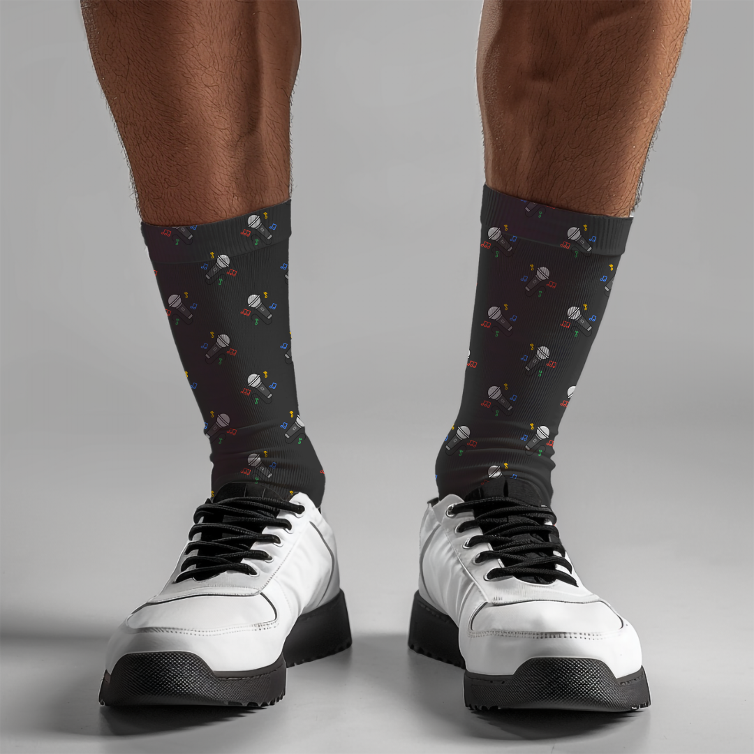 Black socks with colorful microphone pattern worn with white sneakers on a gray background
