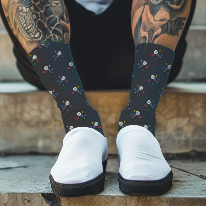 Person wearing black socks with a colorful pattern of microphones and white shoes, sitting on steps.