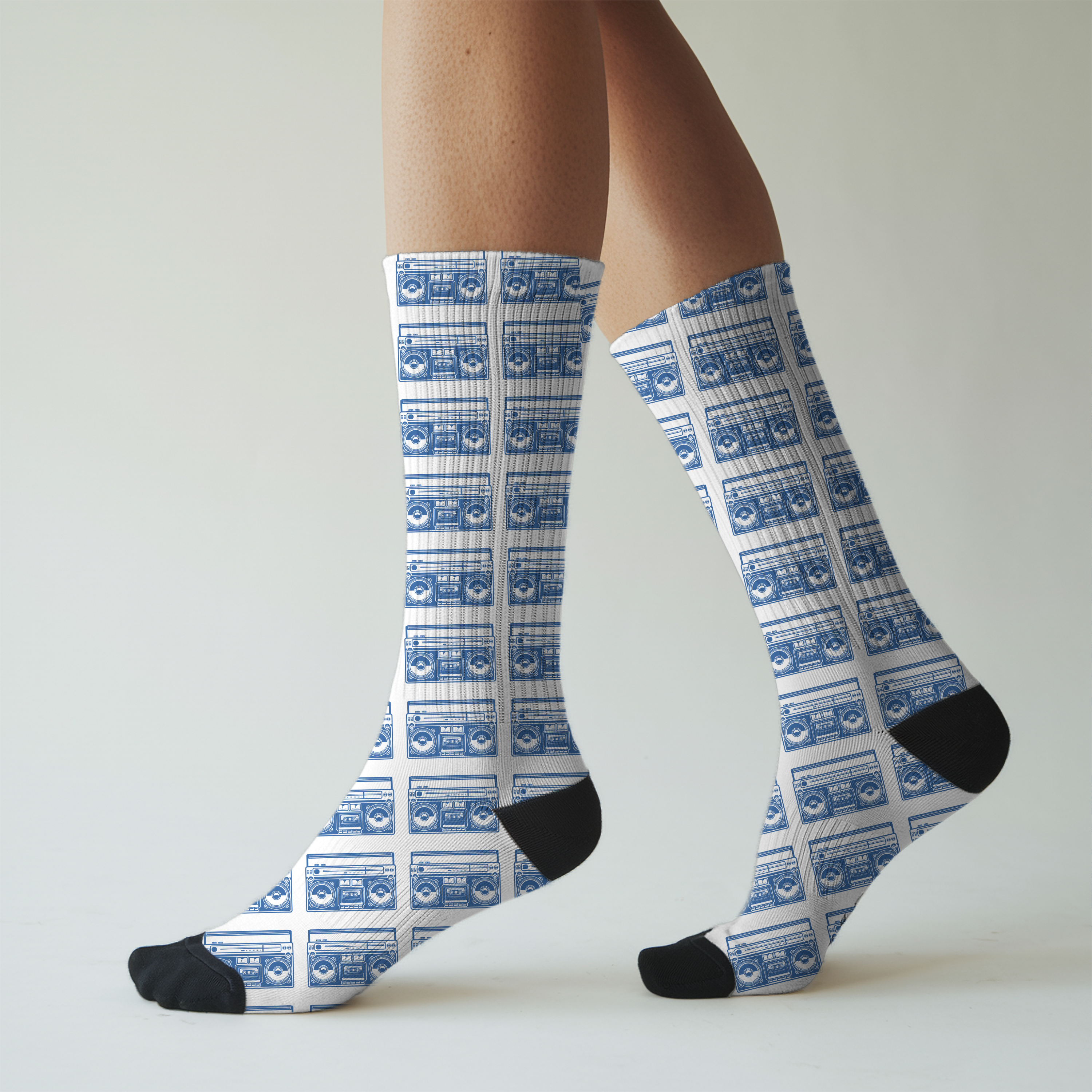 Knee-high socks with blue boom box pattern worn by a person on a plain background