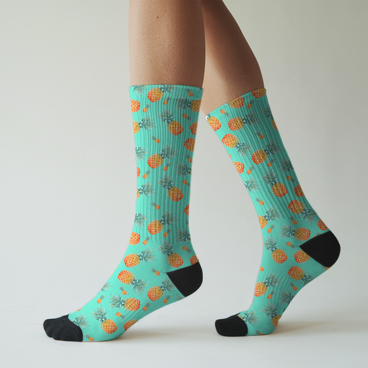 Teal socks with pineapple pattern worn by a person on a light gray background
