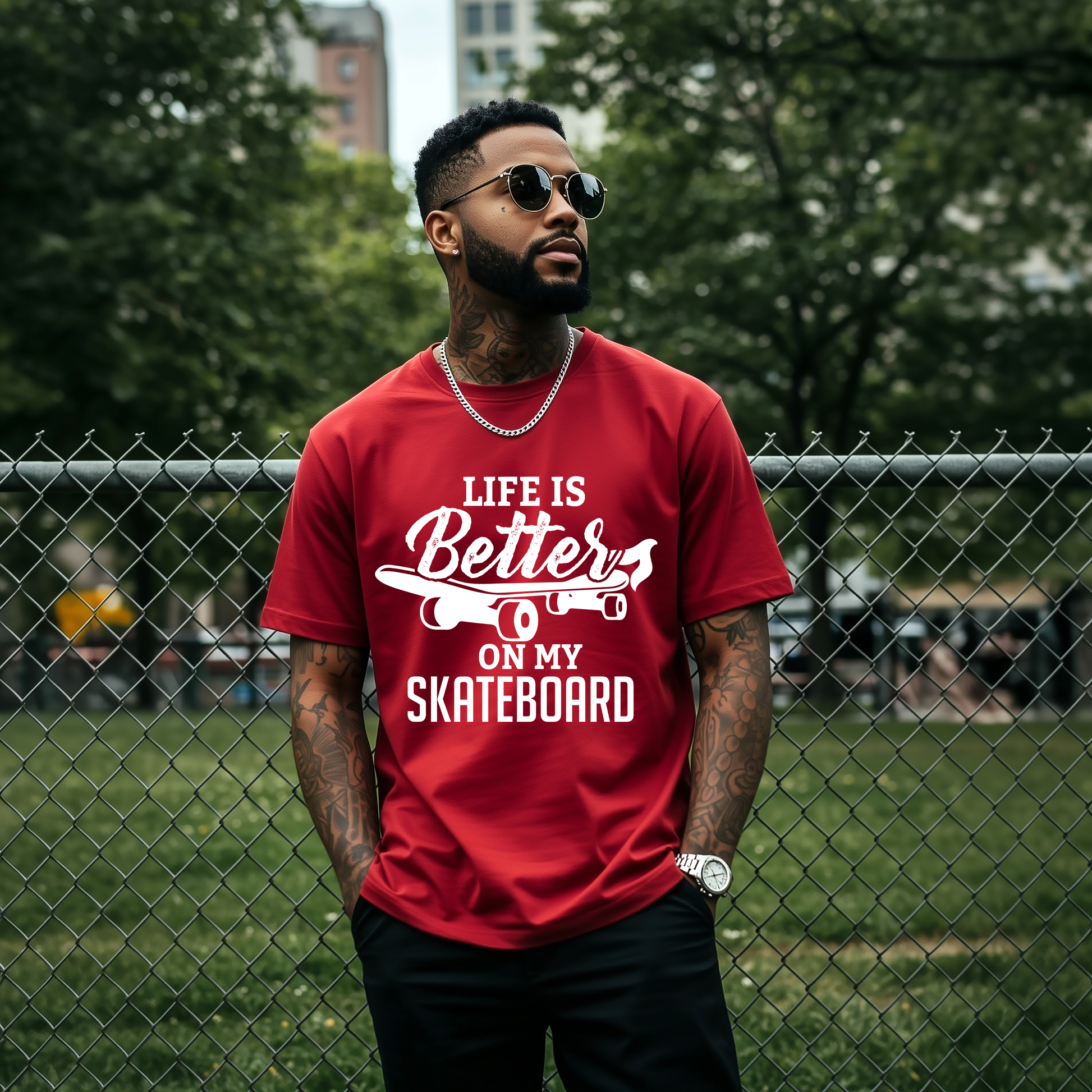 Man wearing a red t-shirt with 'Life is Better on My Skateboard' text, standing in front of a chain-link fence.