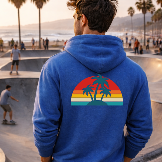 Person wearing a blue hoodie with a palm tree design at a skate park.