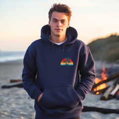 Person wearing a hoodie with a colorful design on a beach at sunset