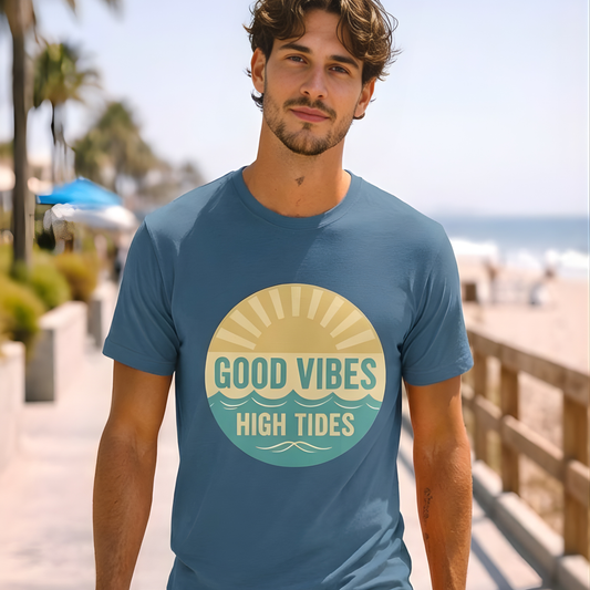 Man wearing a blue t-shirt with 'Good Vibes High Tides' design by a beach.