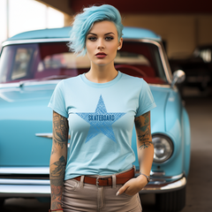 Woman with blue hair and tattoos wearing a light blue skater t-shirt with a star design, standing in front of a vintage turquoise truck.