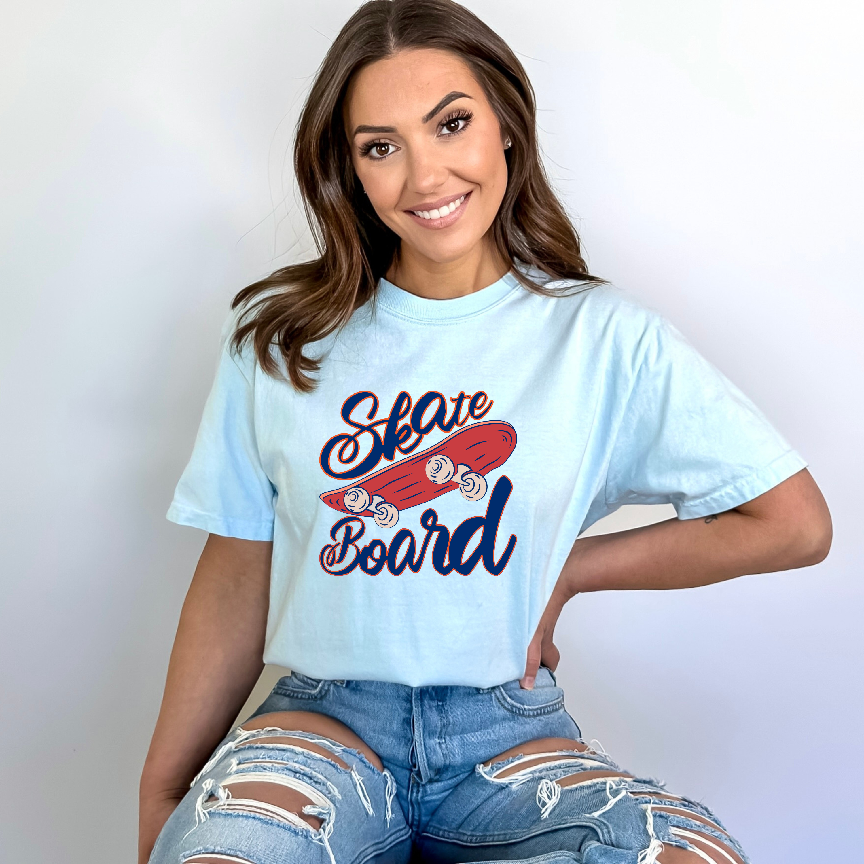 Woman wearing a light blue t-shirt with 'Skate Board' graphic design on a plain background