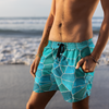 Person wearing blue geometric patterned shorts on a beach