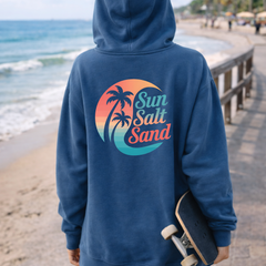 Person wearing a blue hoodie with 'Sun Salt Sand' logo on a beach