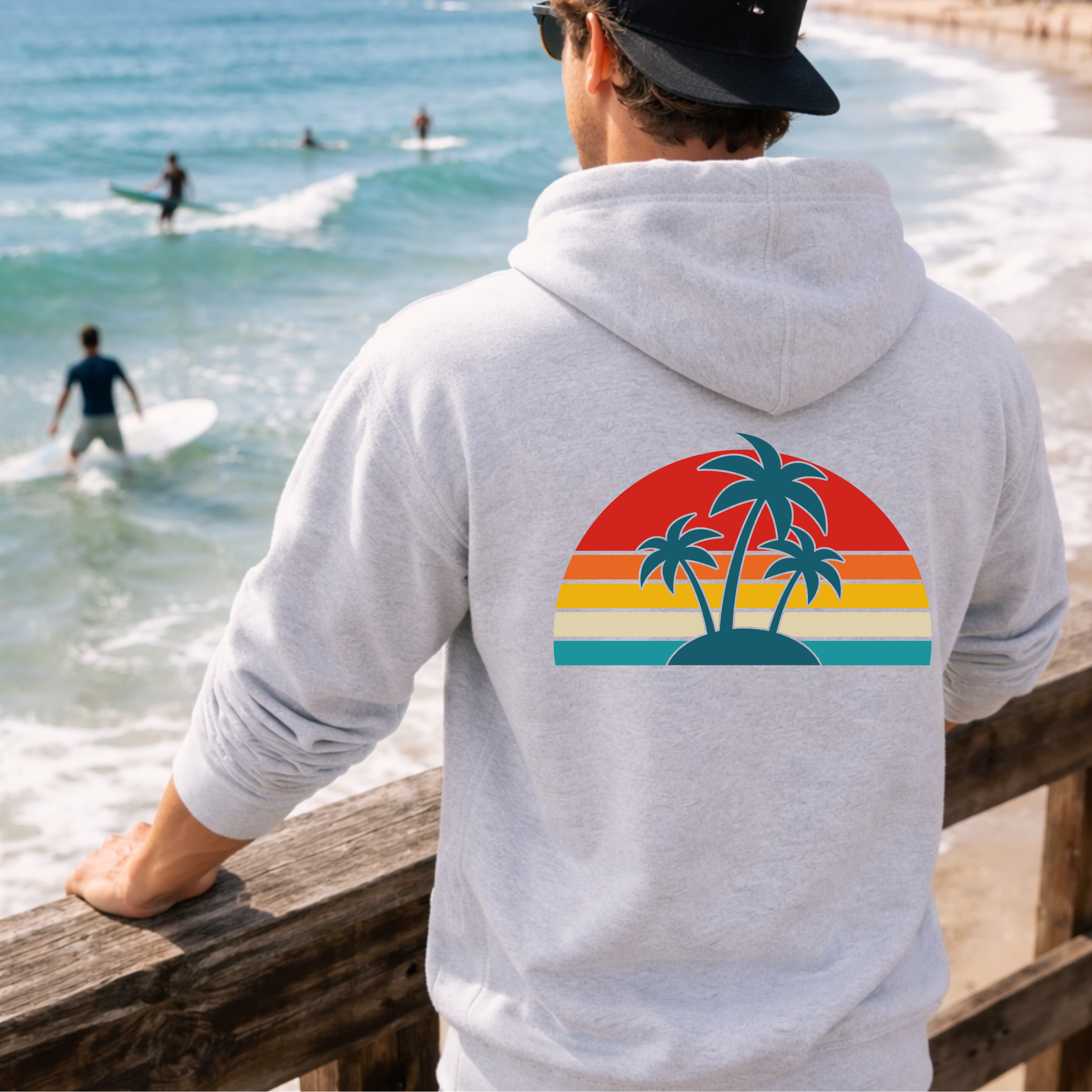 Person wearing a hoodie with a palm tree design by the beach