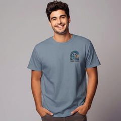 Man wearing a blue t-shirt with a surf club logo on a gray background