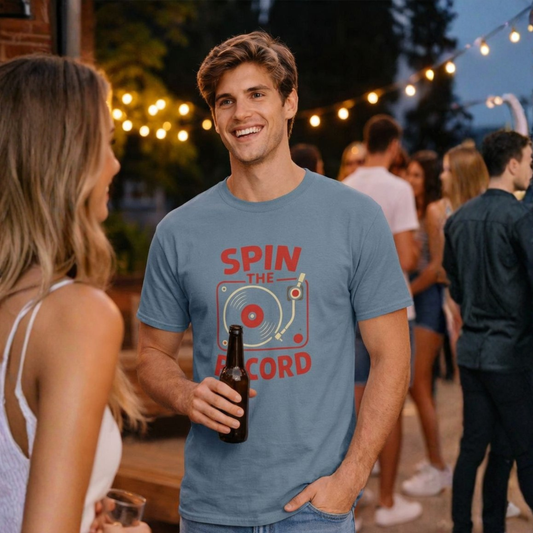 Man wearing a 'Spin the Record' t-shirt holding a beer, standing outdoors with people in the background.