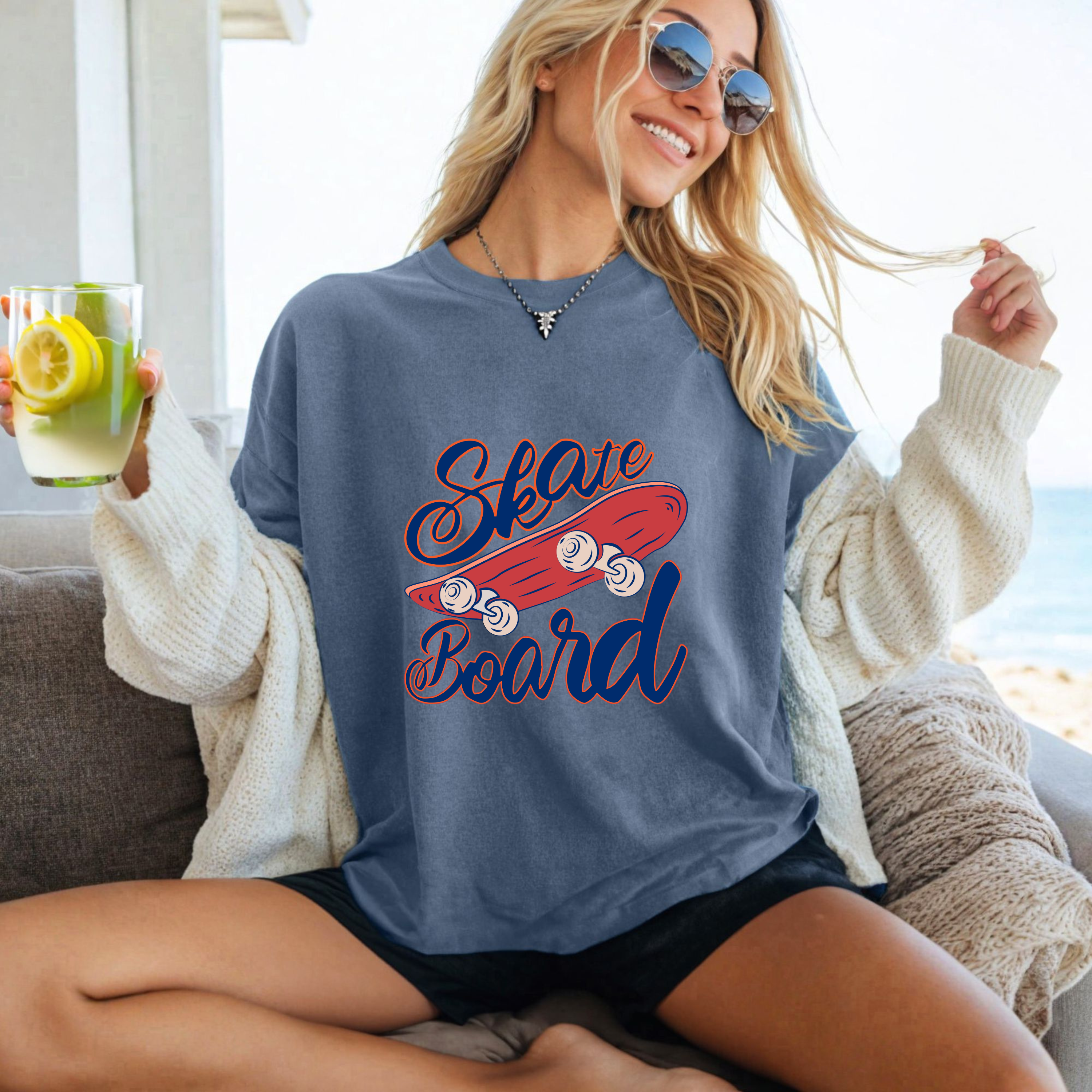 Woman wearing a blue t-shirt with 'Skate Board' text, sitting on a couch.